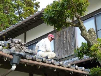屋根の上で応急修理をする従兄弟の左官さん